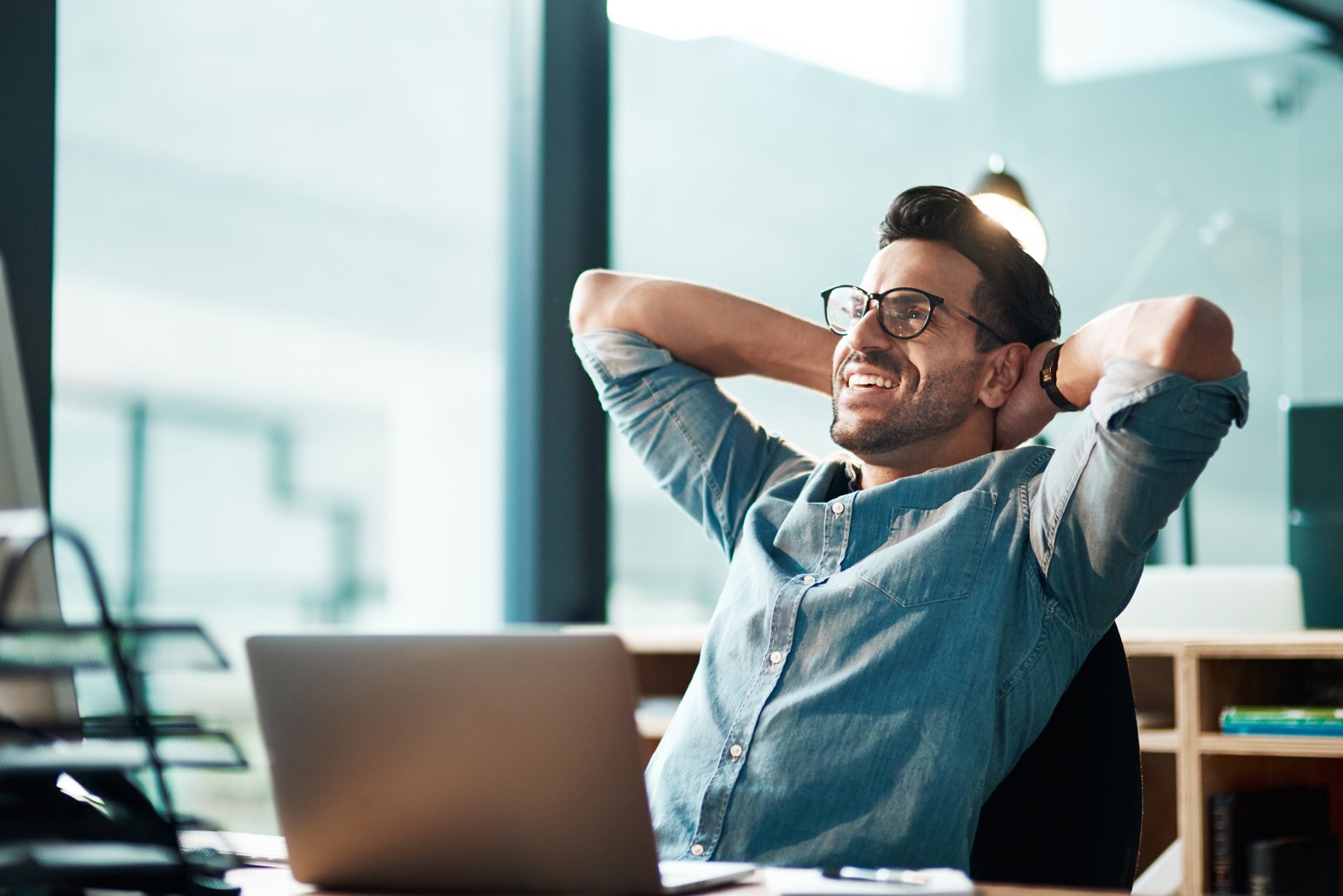 Image of a person relaxed and smiling, leaning in a office hair
