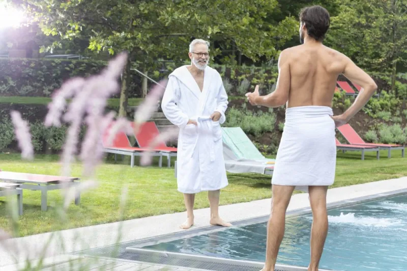Zwei Männer neben einem Schwimmbecken unterhalten sich angeregt.